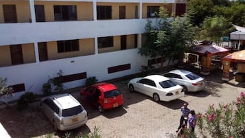 Ein mehrstöckiges Gebäude mit Parkplatz, mehreren Autos und einer Person, die gerade geht.