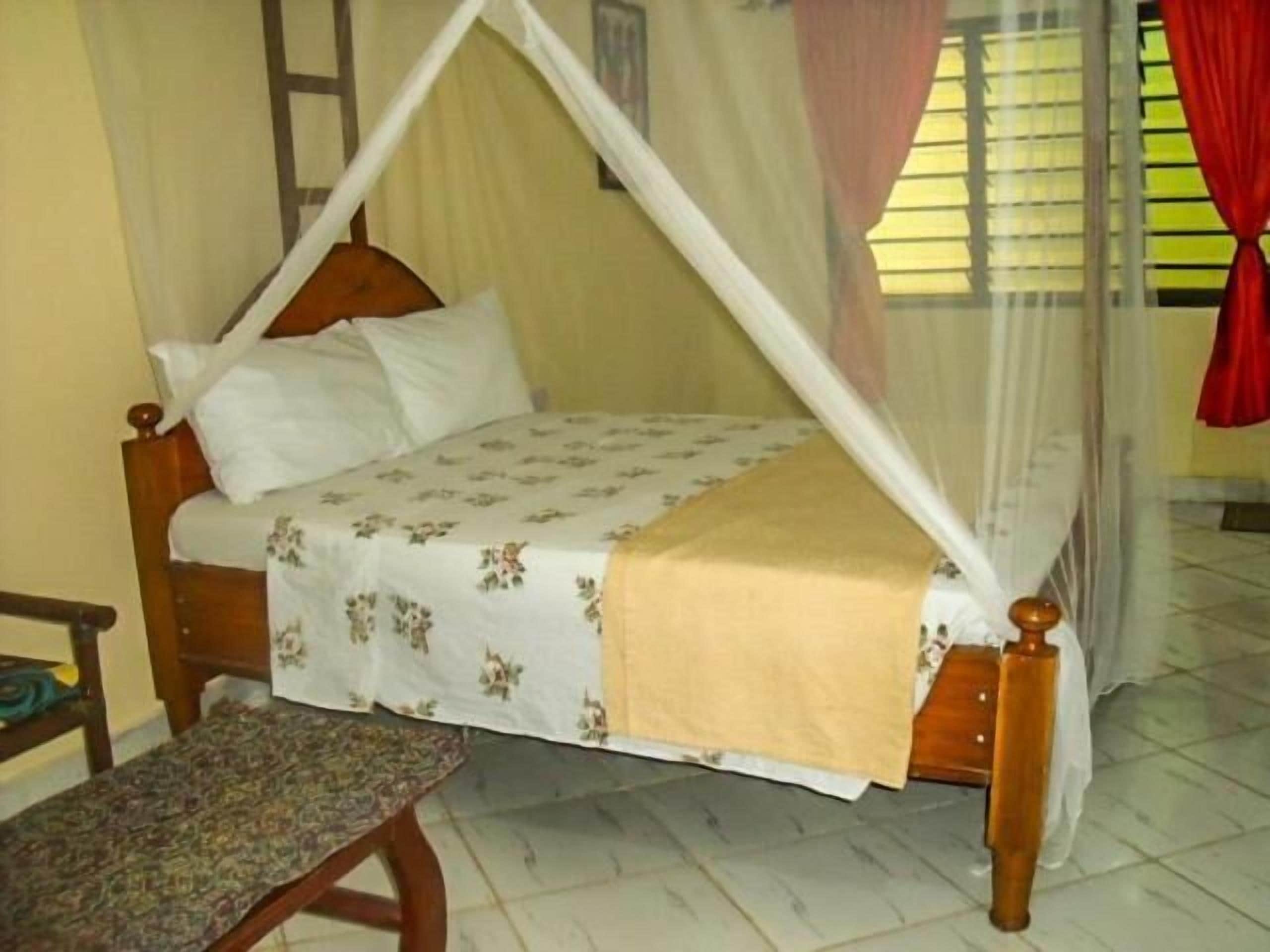 Un lit à baldaquin, un banc et une fenêtre avec des rideaux.