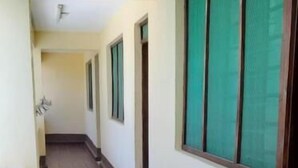 Un pasillo con suelo de baldosas, puertas y ventanas con persianas verdes.