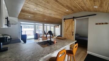 Une cuisine moderne avec un plan de travail en granit, un plafond en bois et une porte coulissante de style rustique.