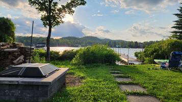 Une vue sur le lac avec un quai, un bateau et un espace barbecue.