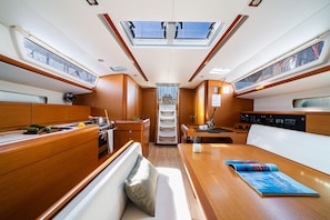 A yacht interior with a dining area, seating, and a central passageway. - Sun-Kissed Sailing Adventure in the Saronic Islands (Nea Peramos)