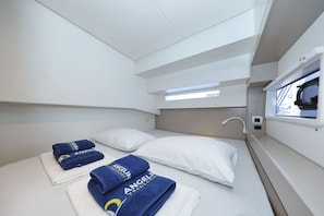 Ein kompakter, gut beleuchteter Raum mit einem Stockbett, ordentlich gefalteten Handtüchern und einem Fenster, das natürliches Licht hereinlässt.