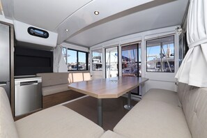 A compact, modern interior with a dining area, a built-in dishwasher, and large windows offering views of the marina. - Sibenik Sun and Beach Sailing Extravaganza: A Croatian Coastal Adventure (Vodice)