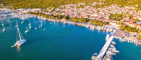 Vista aérea de un pueblo costero con un puerto deportivo, barcos y casas.
