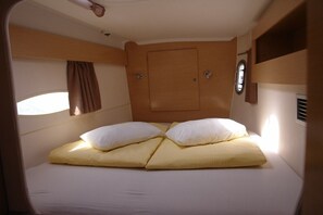 A compact, single-bed room with a wooden headboard, a small window, and a built-in shelf. - Sun-Kissed Sailing Adventure in Northern Croatia (Punat)