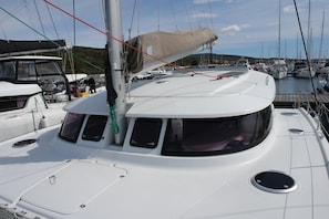 A sailboat docked at a marina with multiple boats, a covered area, and a view of the water.