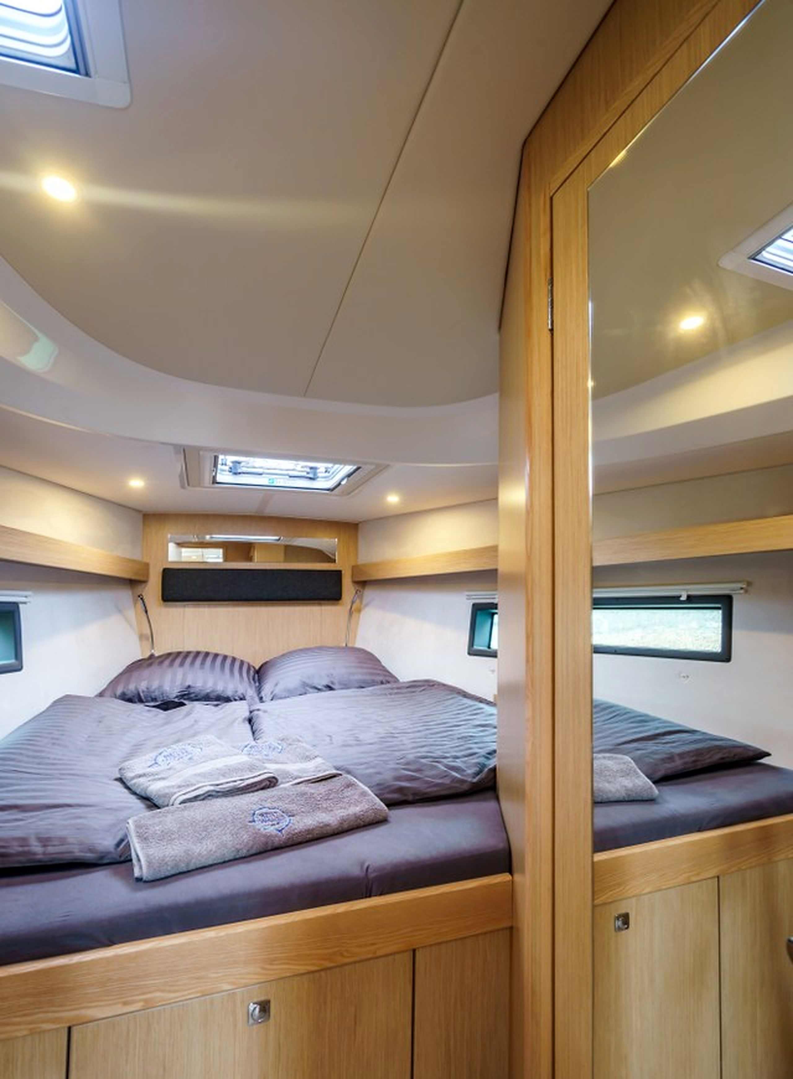A compact, well-lit interior with a bunk bed, built-in storage, and skylights.