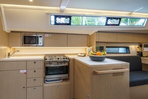 Cocina compacta con microondas, estufa, horno y un lavamanos pequeño.