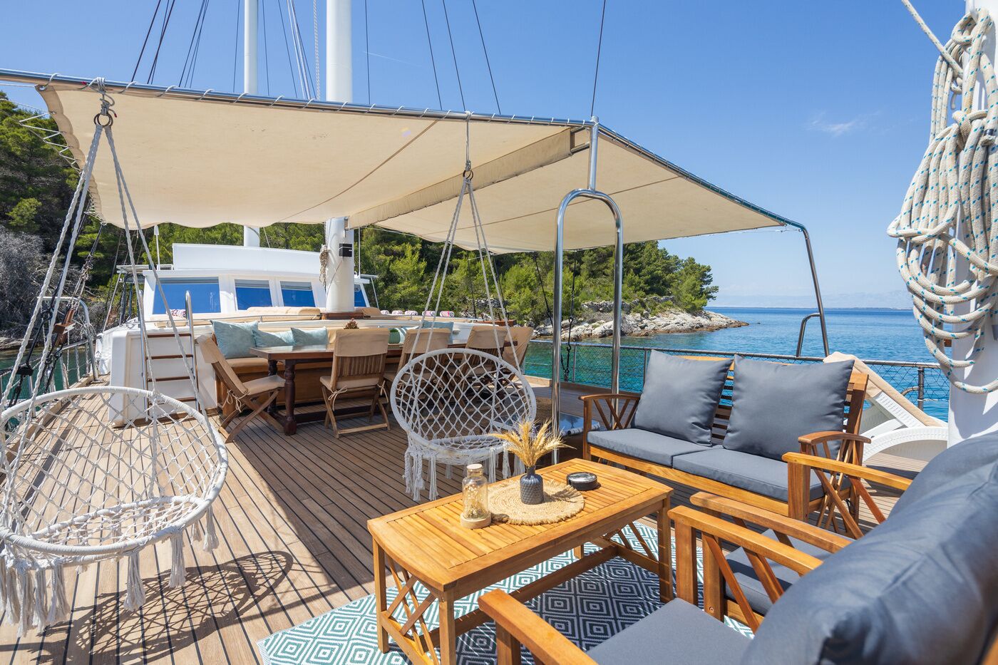 A deck with outdoor seating, a table, and a hanging chair.