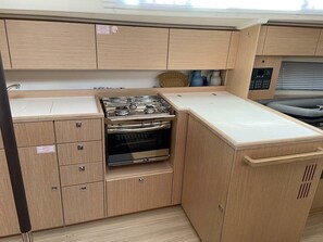 Eine kleine Küchenzeile mit Herd, Backofen und Stauraumschränken.