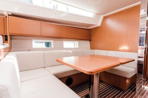 A compact, well-lit interior with a cushioned seating area, a small table, and a window providing natural light. - Sun-Kissed Sailing Adventure in the Ionian Islands, Lefkada (Lefkada)