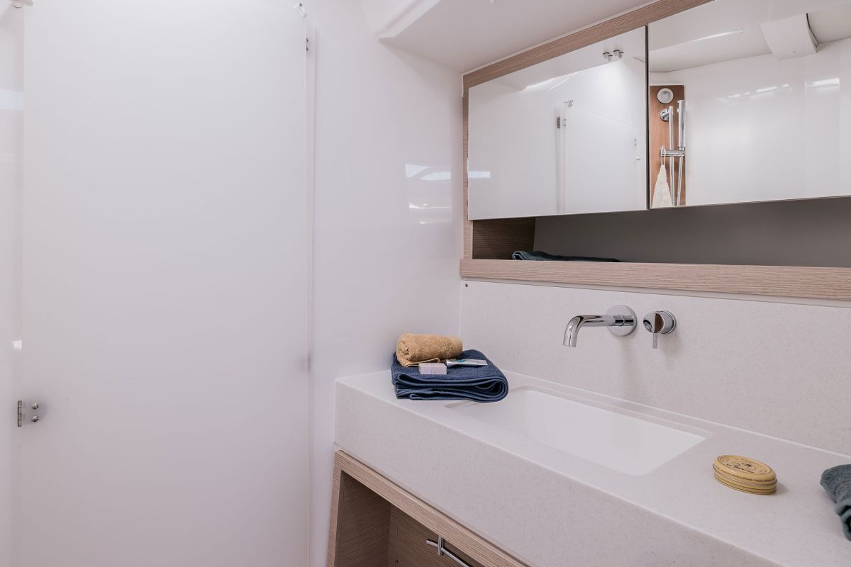 Une salle de bain avec un lavabo blanc, un miroir, une serviette et un meuble en bois.