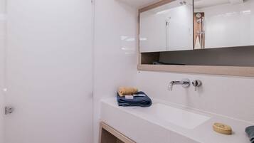 Une salle de bain avec un lavabo blanc, un miroir, une serviette et un meuble en bois.