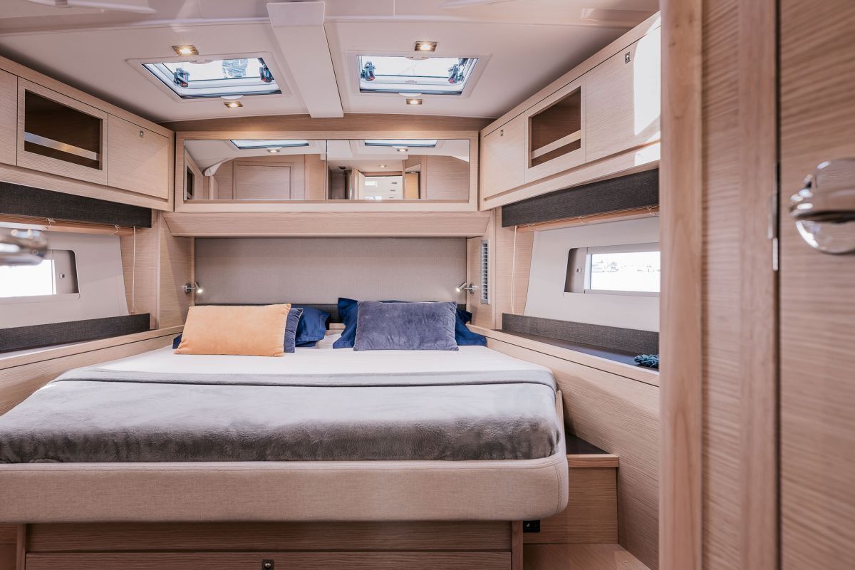 Ein kompaktes Wohnmobil-Interieur mit Bett, Dachfenstern und einer Küchenzeile.