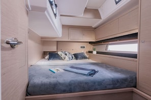 Un intérieur compact et bien éclairé, comprenant un lit, des placards de rangement et une fenêtre laissant entrer la lumière naturelle.