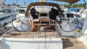 A boat's deck with a wooden table, steering wheel, and control panel. - Dubrovnik Delight: A Sun-Kissed Sailing Experience (Komolac)