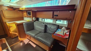 A compact interior with a sofa, a small table, a microwave, and a fan. - Dubrovnik Delight: A Sun-Kissed Sailing Experience (Komolac)