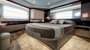 Quarto moderno com cama curva, armários embutidos e janelas amplas.