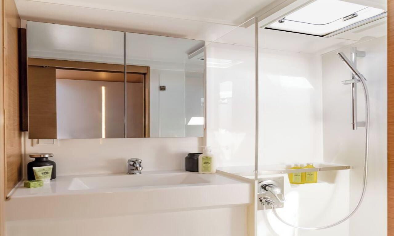 Uma casa de banho moderna com um espelho grande, uma sanita branca e uma cabine de duche em vidro.