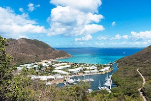 Un pueblo costero con un puerto deportivo, edificios y montañas al fondo.