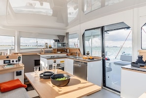 Una cocina compacta moderna con estufa, lavamanos y zona de comedor en un yate.