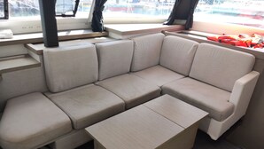 Un interior moderno con un sofá seccional color beige, una mesa de centro de madera y un ventanal con vistas a barcos.