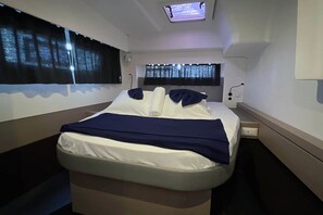 A hotel room with a bed, a TV, a window with curtains, and a bedside table.
