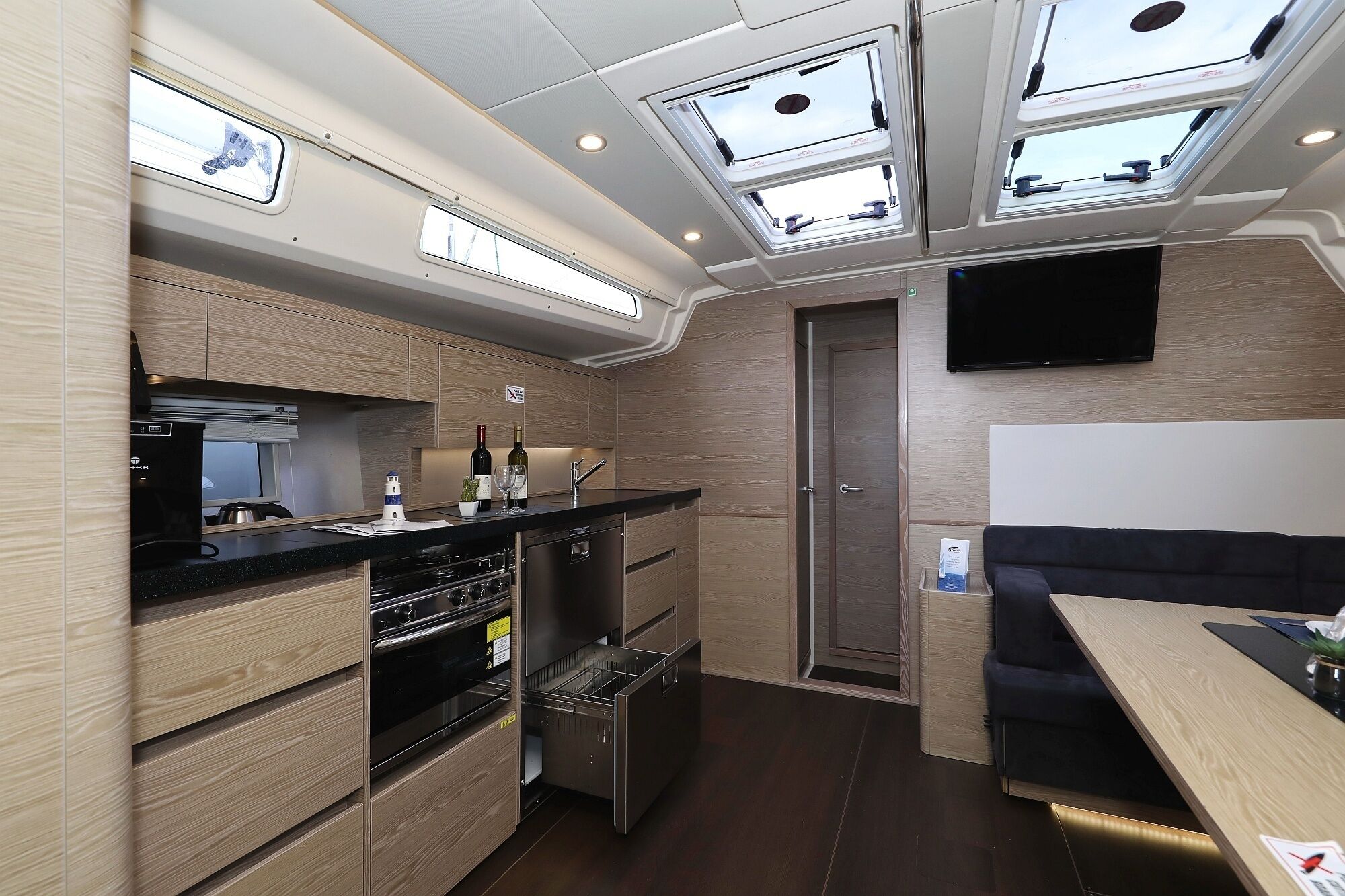Een compacte keuken met inbouwapparatuur, een zithoek met een flatscreen-tv en dakramen.