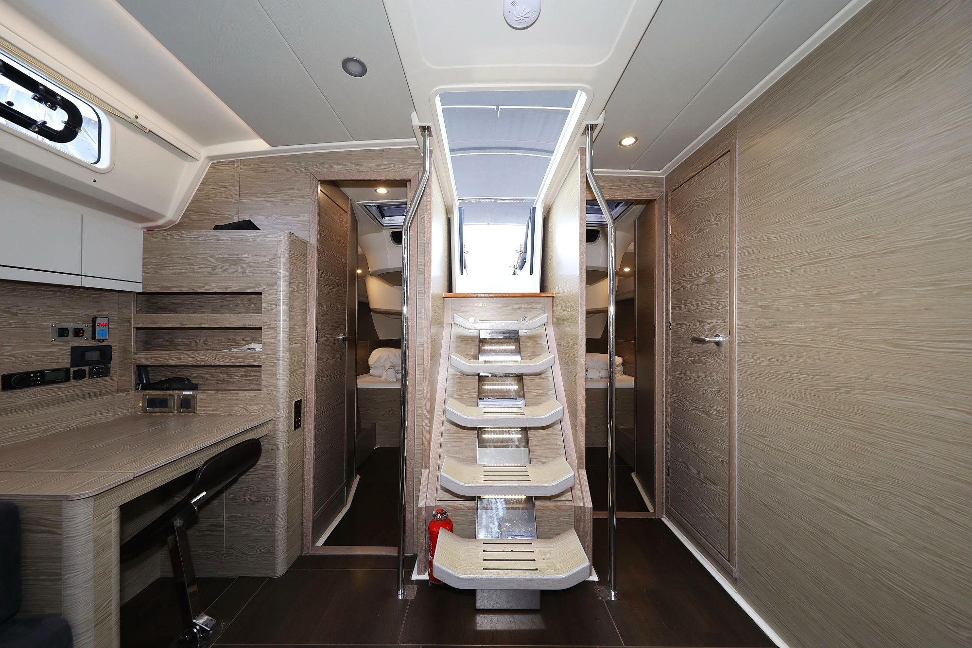 A modern interior with a central staircase, wooden paneling, and a control panel with various buttons and displays.