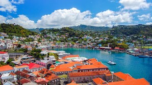 A coastal town with buildings, a harbor, and mountains in the background.