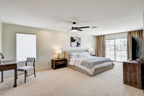 Ein Schlafzimmer mit Bett, Schreibtisch, Stuhl, Deckenventilator und Fernseher.