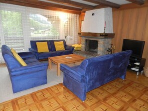 Un salon avec une cheminée, un ensemble de canapés, un téléviseur et un sol à motifs.