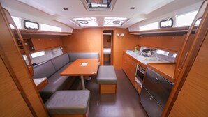 A compact interior with a dining table, bench seating, a kitchenette, and a small window. - Sun-kissed Sailing Adventure in Split-Dalmatia, Croatia (Seget Donji)