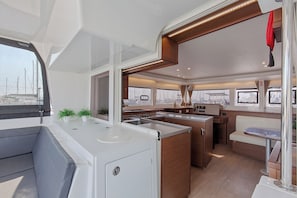 A compact kitchen with a central island, a dining area, and a seating space. - Sun-Kissed Sailing Adventure in Islas Sarónicas (Alimos)