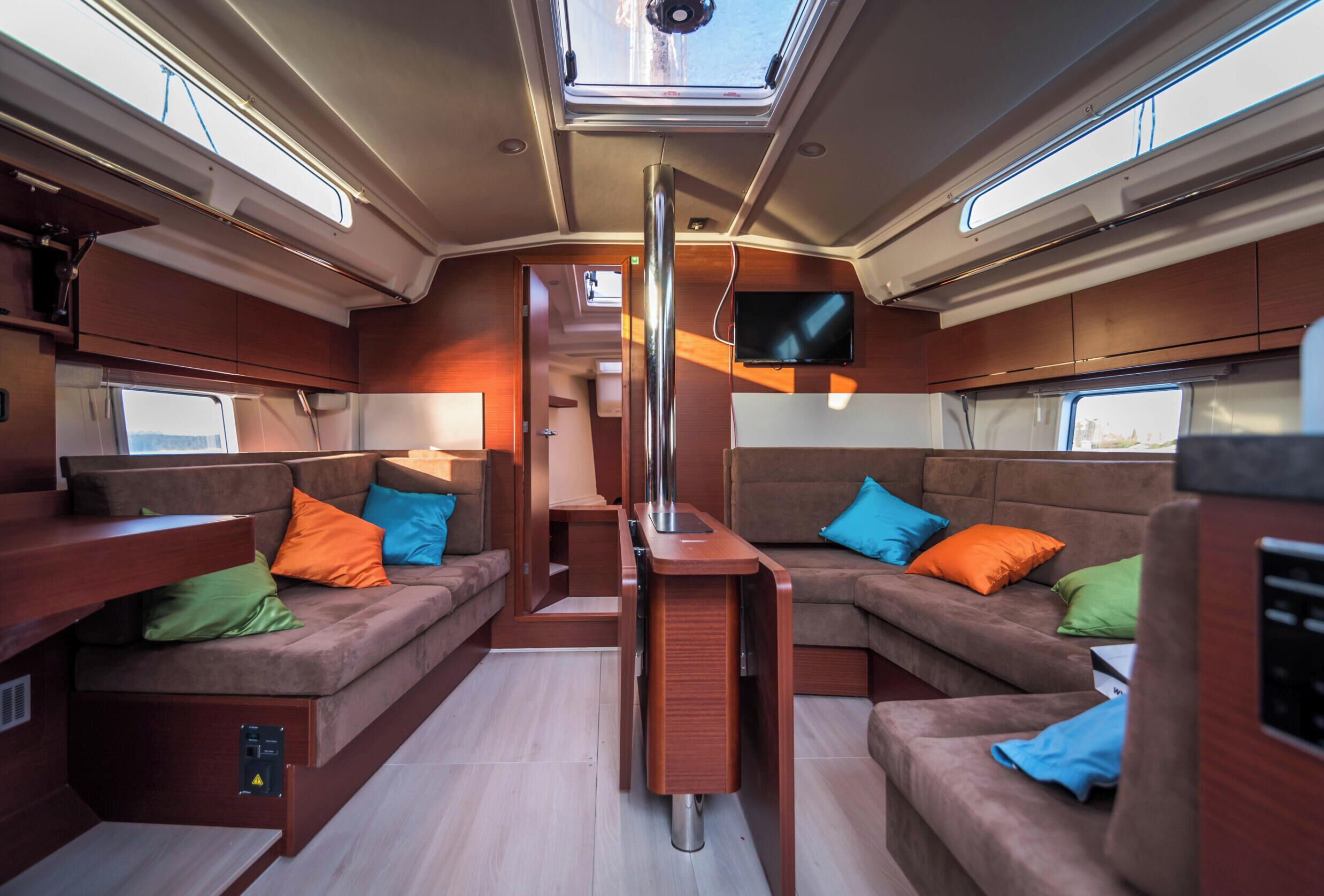 A compact interior with a central table, cushioned seating, and a mounted TV.