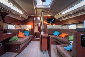A compact interior with a central table, cushioned seating, and a mounted TV. - Sun-Kissed Sailing: An Unforgettable Beach Experience in Istria, Croatia (Medulin)