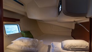 Una cabana petita amb una finestra, un llit amb almoadins i un llit ben fet.