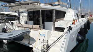 A marina with multiple boats docked, featuring a white boat with 'Freedom' and 'N.E. 342' visible, and a smaller boat with 'TT FREEDOM' on its side. - Sun-Kissed Sailing Adventure in Islas Sarónicas (Alimos)