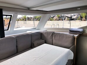A modern interior with a sofa, a small table, and a view of rocks and plants through large windows. - Sun-Kissed Sailing Adventure in the Majestic Islas Baleares (Ibiza / Eivissa)