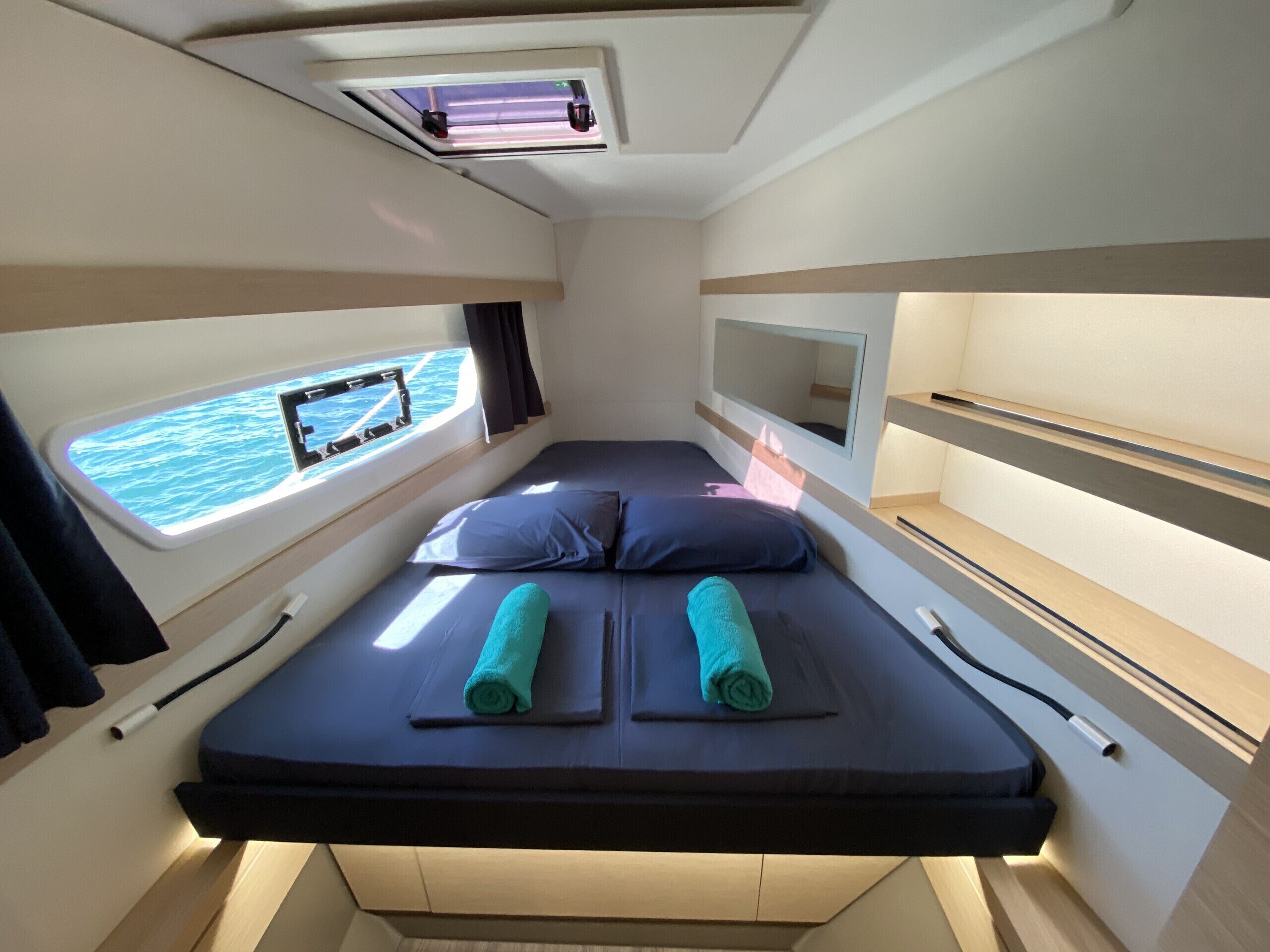 A compact cabin with a bed, a window with a view, a small table, and a ceiling light.