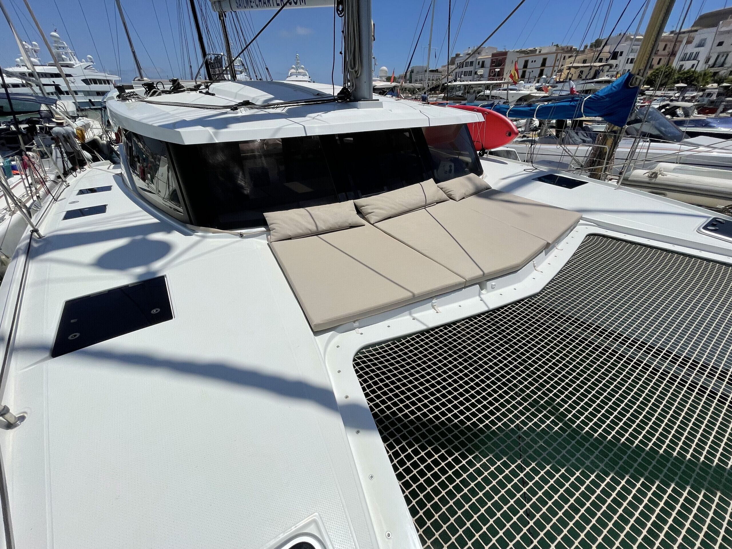 Ein Bootsdeck mit überdachter Sitzgelegenheit, einem Mast und weiteren Booten im Hintergrund.