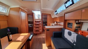 A compact interior with a dining area, a sofa, a small kitchen, and a galley with a sink and stove. - Sun-kissed Sailing Adventure in Split-Dalmatia, Croatia (Trogir)