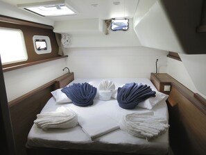 A compact cabin with a bed, two windows, a small fan, and a control panel.