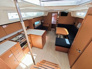Un interior compacto con comedor, una pequeña kitchenette y una cama plegable.