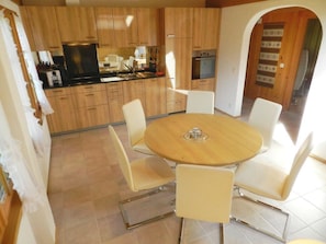 A modern kitchen with wooden cabinets, a dining table with chairs, and a television. - Abendrot Appartement/Fewo, Dusche oder Bad, WC 2-Bettwohnung by Interhome (Gstaad)