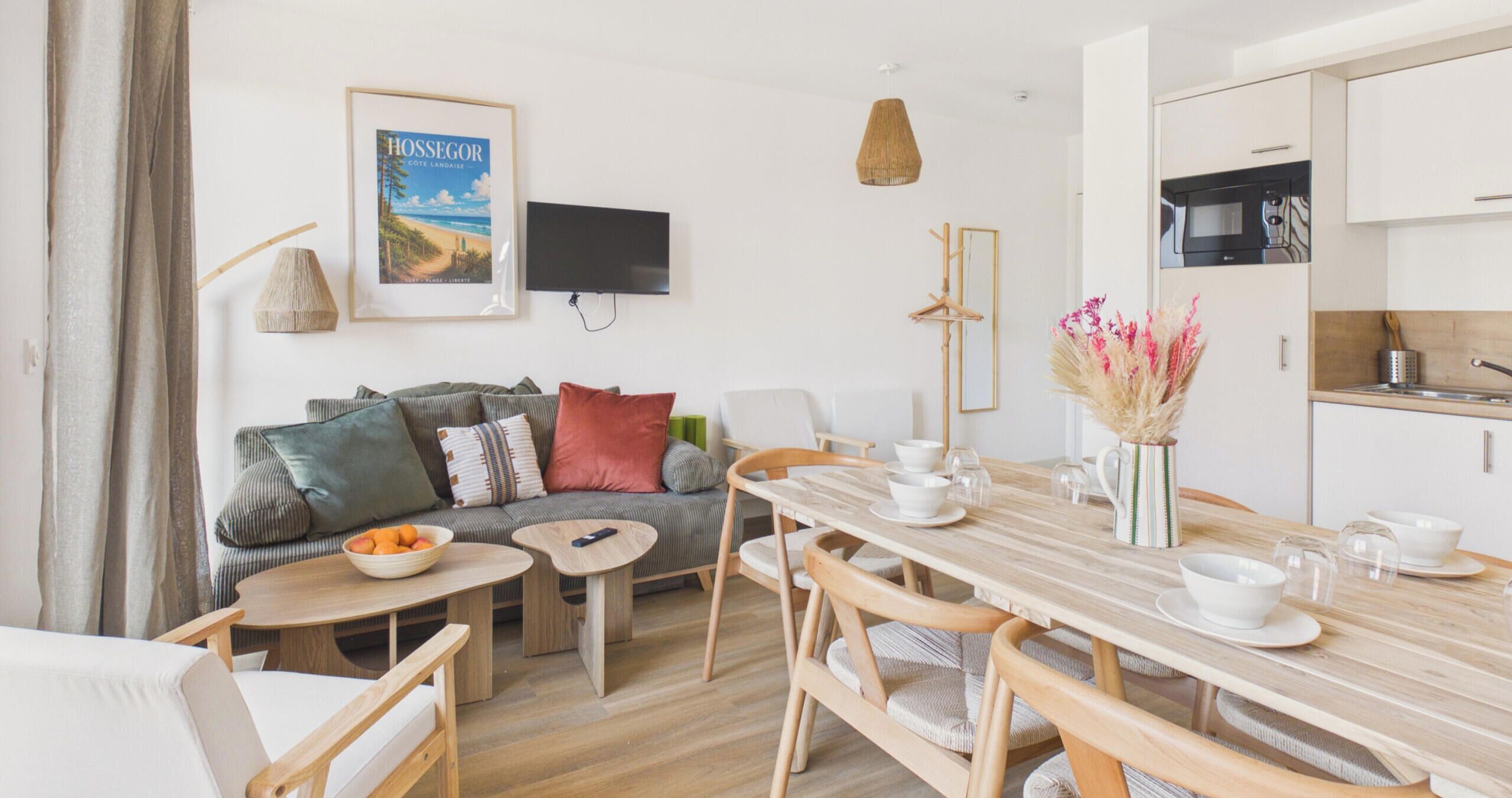 A modern living room with a sofa, coffee table, dining table, and kitchen area.