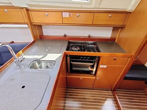 A compact kitchenette with a sink, stove, oven, and storage cabinets. - Sun-Kissed Sailing Adventure in Zadar, Croatia (Bibinje)