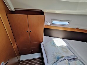 Ein kompaktes Wohnmobil-Interieur mit einem Bett, einem Holzkasten und einem kleinen Fenster.