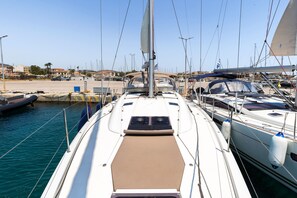 A marina with multiple yachts docked, a clear sky, and a calm sea.